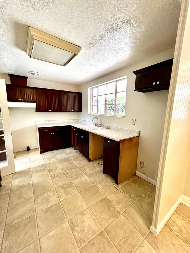 356 E Main St, Colquitt, GA 39837 - kitchen featuring a sink, light countertops, a textured ceiling, dark brown cabinetry, and light tile patterned floors