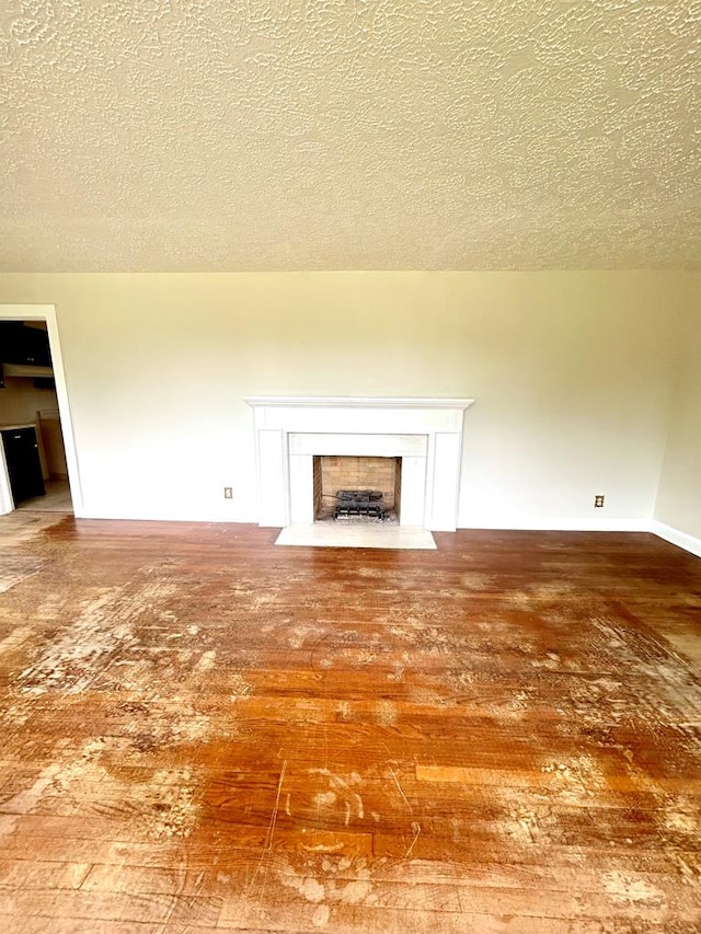 356 E Main St, Colquitt, GA 39837 - unfurnished living room featuring hardwood / wood-style flooring, a fireplace with flush hearth, a textured ceiling, and baseboards