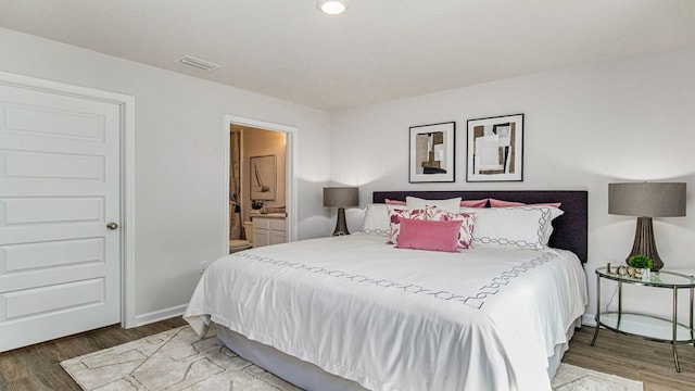 bedroom with ensuite bath and wood-type flooring