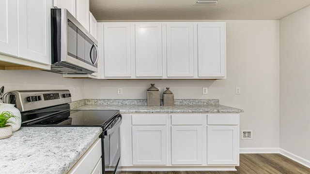 kitchen with hardwood / wood-style floors, white cabinets, a textured ceiling, and appliances with stainless steel finishes