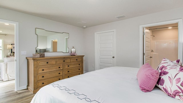 bedroom featuring ensuite bathroom and light wood-type flooring