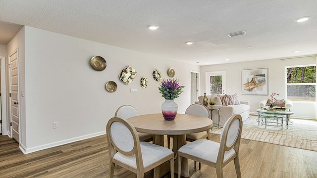 dining area featuring a textured ceiling, plenty of natural light, and dark wood-type flooring