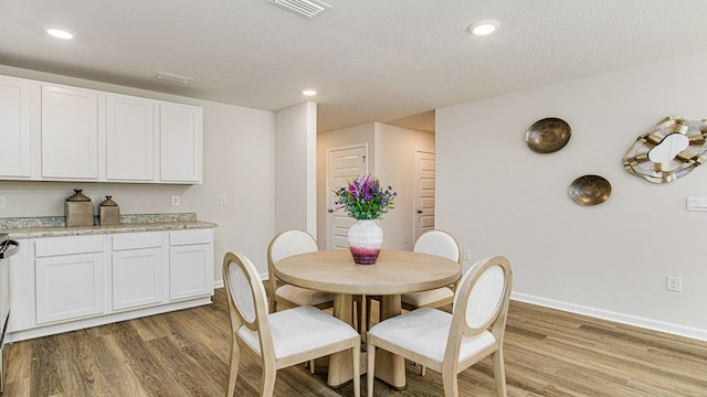 dining space featuring hardwood / wood-style floors and a textured ceiling