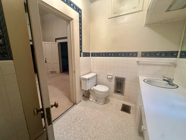 bathroom with tile patterned flooring, toilet, vanity, visible vents, and tile walls