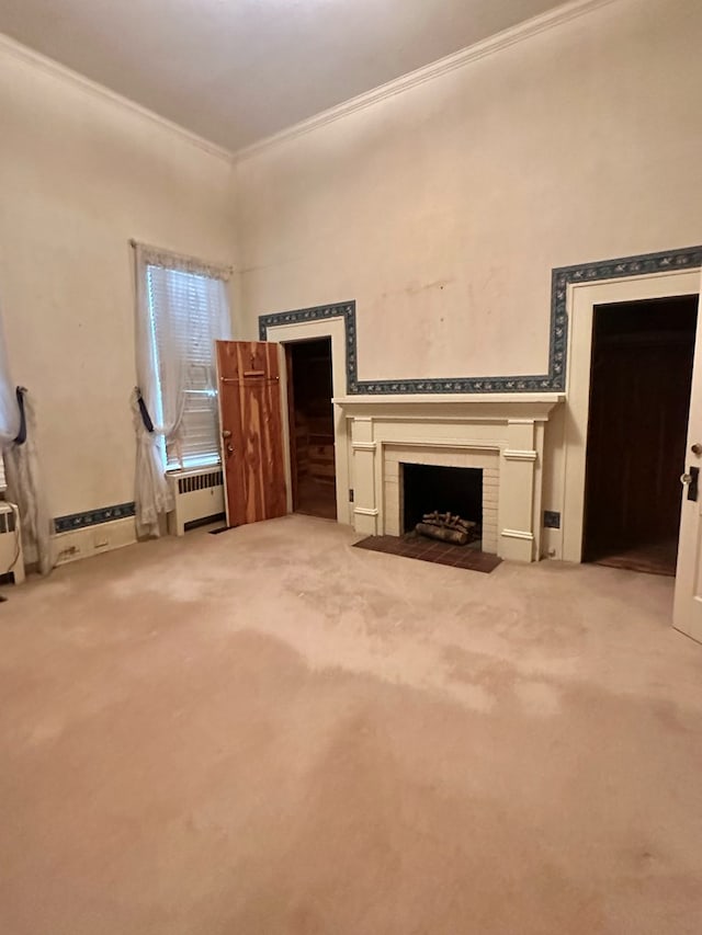 unfurnished living room with radiator heating unit, ornamental molding, carpet flooring, and a fireplace with flush hearth