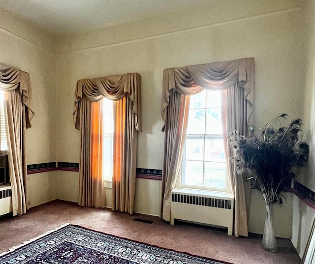 interior space with radiator heating unit, visible vents, and carpet flooring