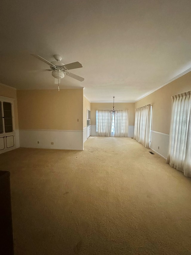 empty room with light carpet, crown molding, visible vents, and ceiling fan with notable chandelier