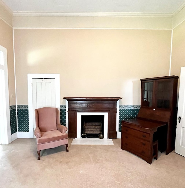 living area with a fireplace with raised hearth, ornamental molding, and carpet