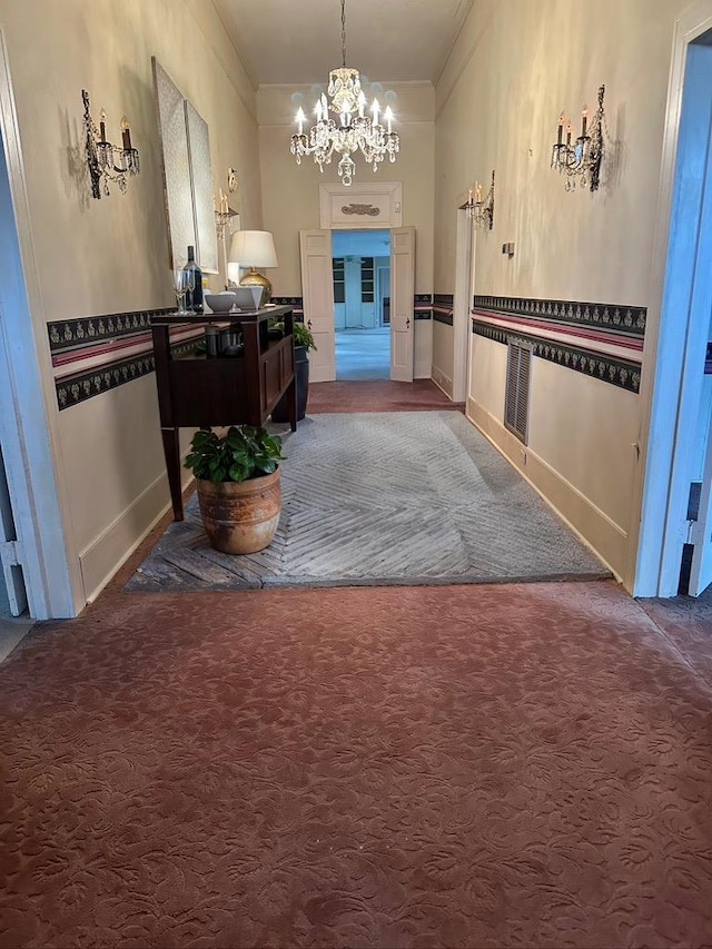 corridor featuring baseboards, carpet, an inviting chandelier, and crown molding