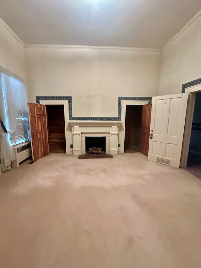 unfurnished living room featuring crown molding, visible vents, radiator heating unit, a fireplace with flush hearth, and carpet flooring