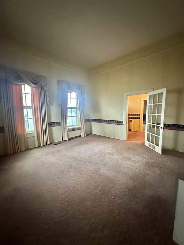 carpeted spare room featuring french doors and radiator