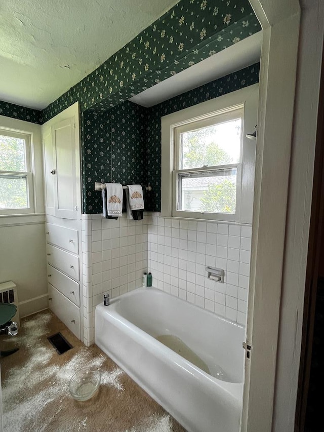 full bath with a bath, wallpapered walls, visible vents, and a textured ceiling