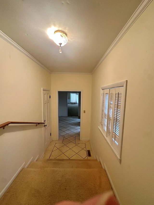 hallway featuring light tile patterned floors, baseboards, and crown molding