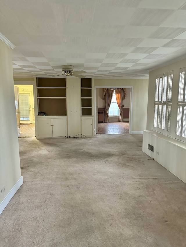 unfurnished living room featuring built in shelves, light carpet, and baseboards