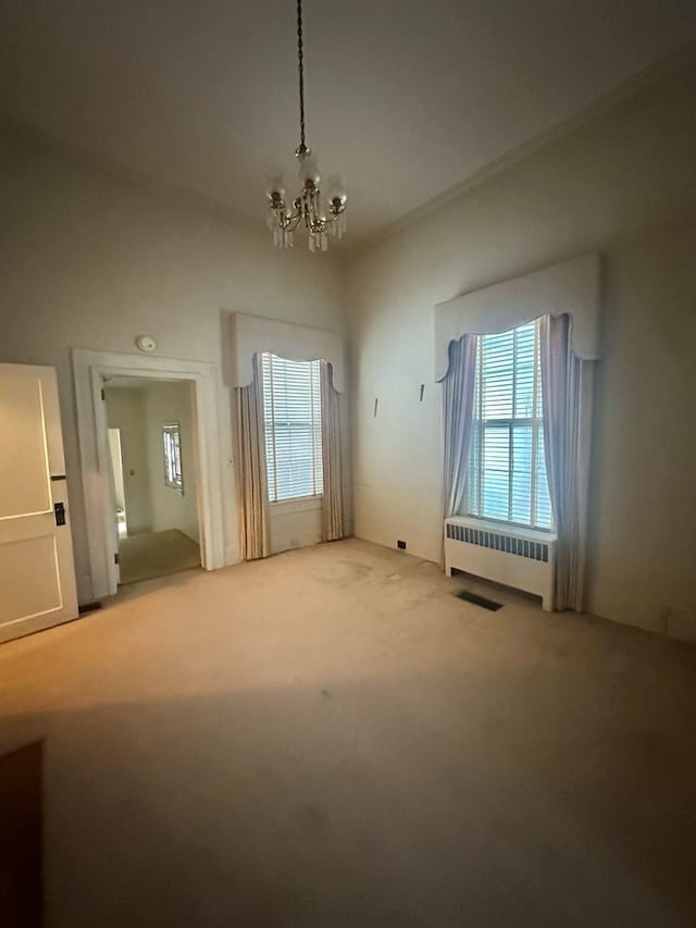 interior space with radiator, a healthy amount of sunlight, carpet, and a chandelier