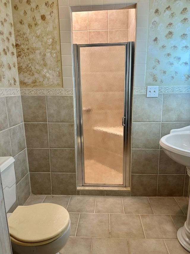 bathroom featuring toilet, tile patterned flooring, a shower stall, and tile walls