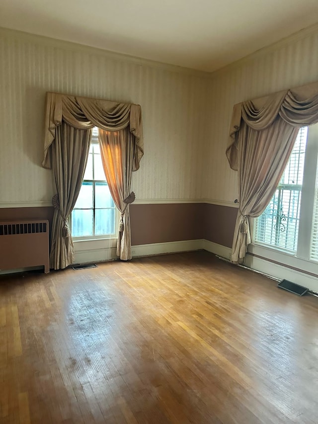 empty room with visible vents, radiator heating unit, and wood finished floors