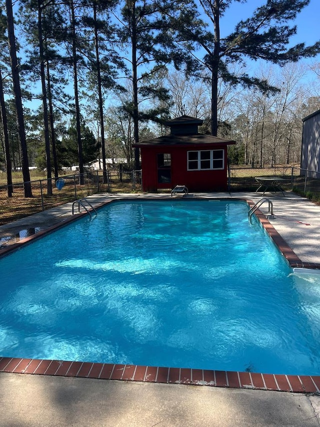 view of pool with an outbuilding, a fenced in pool, fence, and a patio area