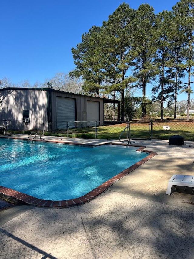 community pool with an outbuilding, fence, and a patio area