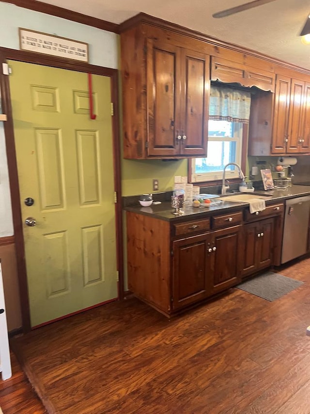 kitchen with dark countertops, dark wood-style flooring, dishwasher, and a sink