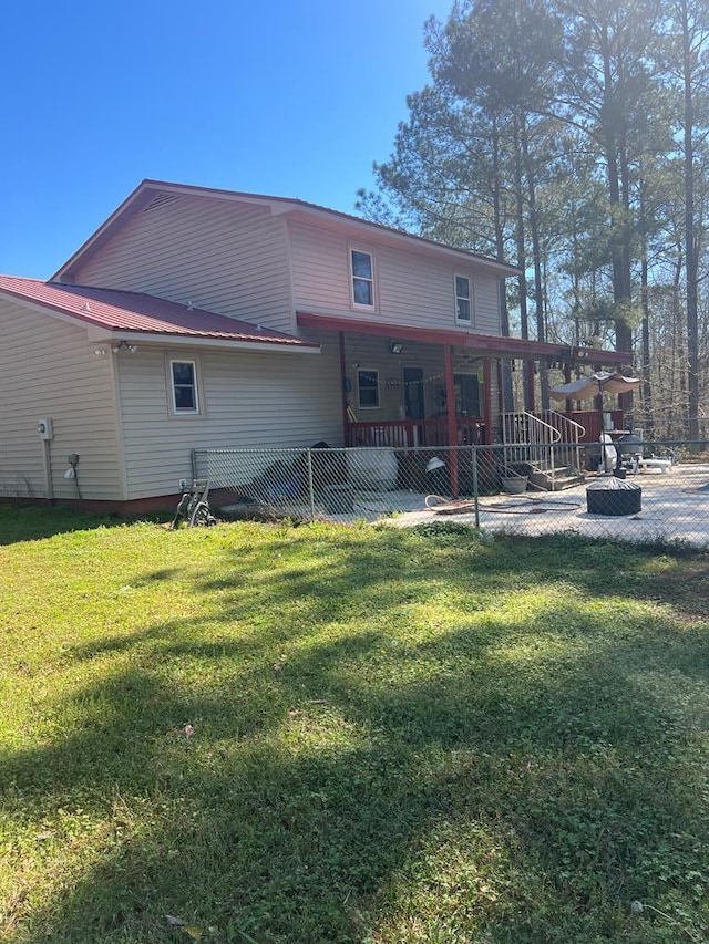 back of property with a yard and metal roof