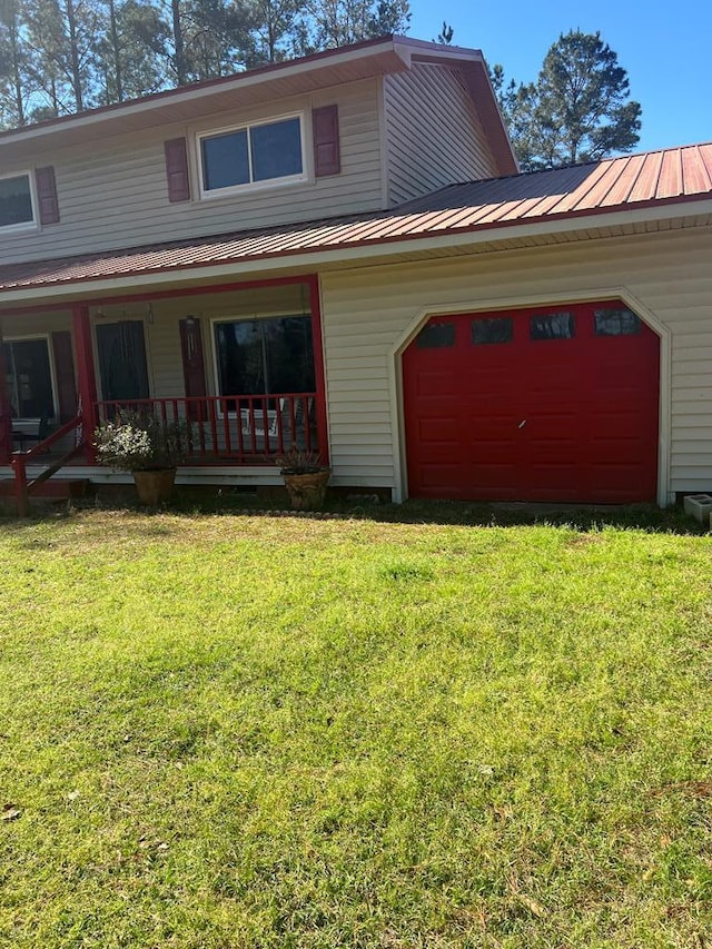 view of front of property featuring a front yard, driveway, a porch, an attached garage, and metal roof