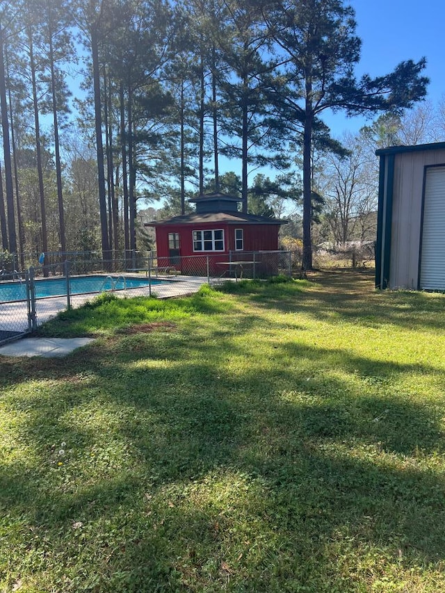 view of yard featuring a fenced in pool, an outbuilding, and fence