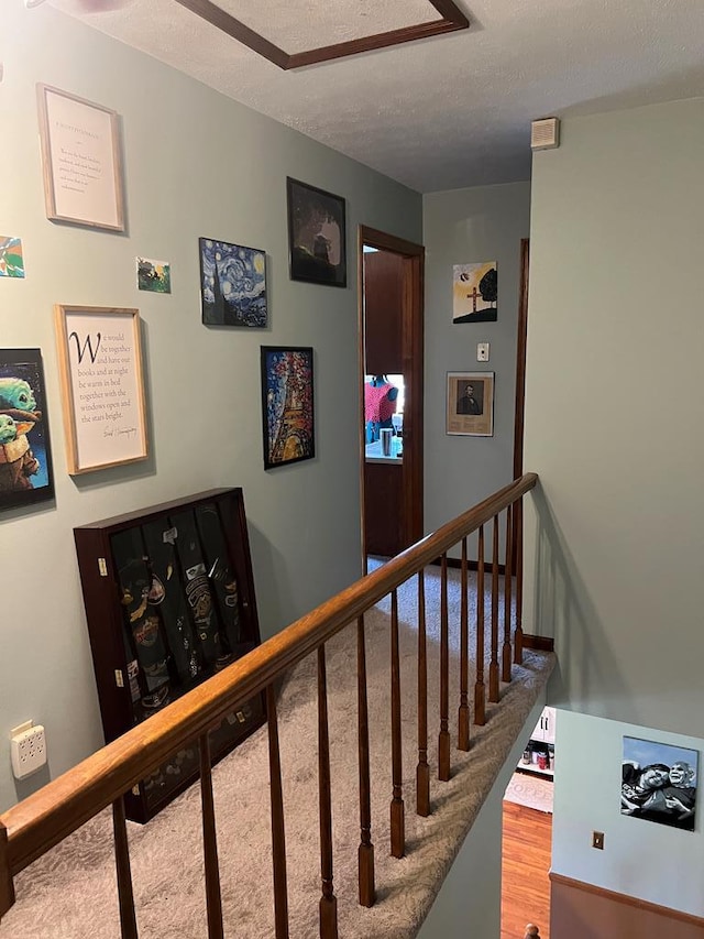 staircase featuring a textured ceiling and wood finished floors