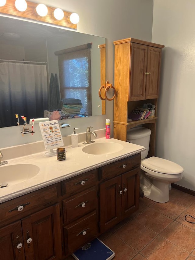 bathroom featuring tile patterned flooring, double vanity, toilet, and a sink