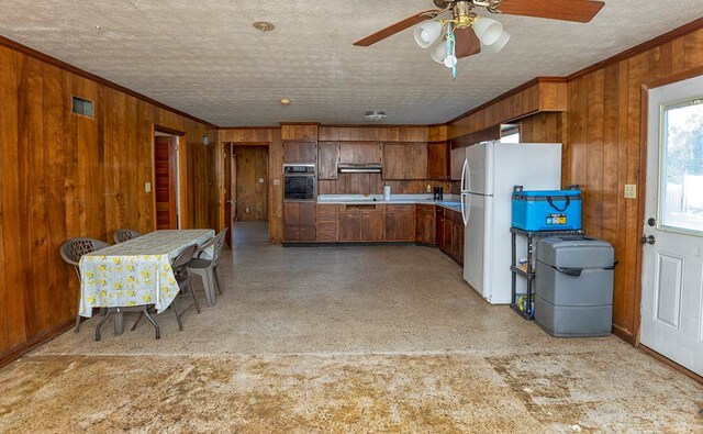 kitchen featuring oven, wood walls, ornamental molding, and white fridge