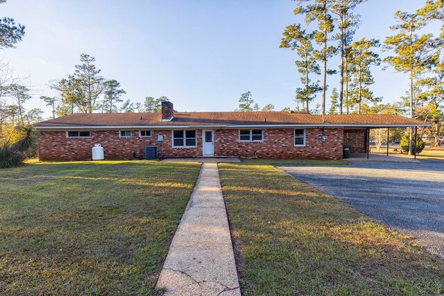 ranch-style house featuring central AC unit, a front yard, and a carport