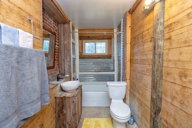 bathroom with toilet, wood walls, and vanity