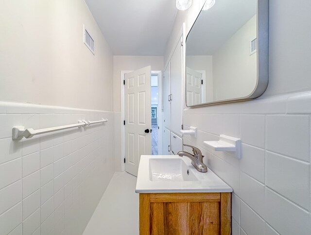 bathroom featuring vanity and tile walls