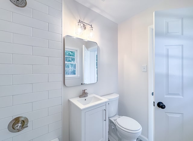 bathroom featuring toilet, a tile shower, and vanity