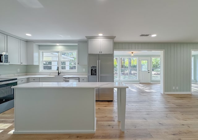 kitchen with sink, a center island, white cabinetry, light hardwood / wood-style flooring, and appliances with stainless steel finishes