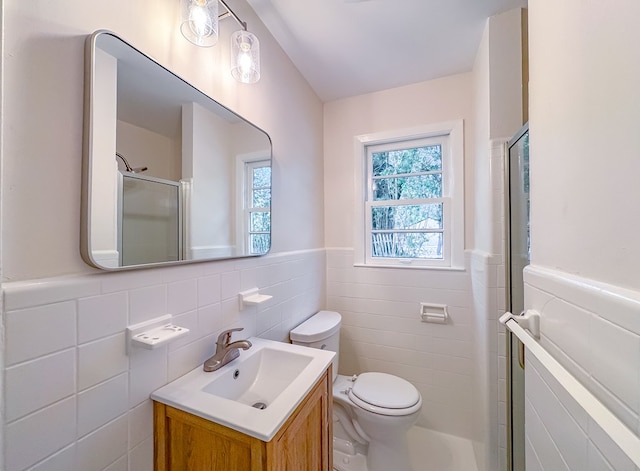 bathroom featuring vanity, toilet, walk in shower, and tile walls