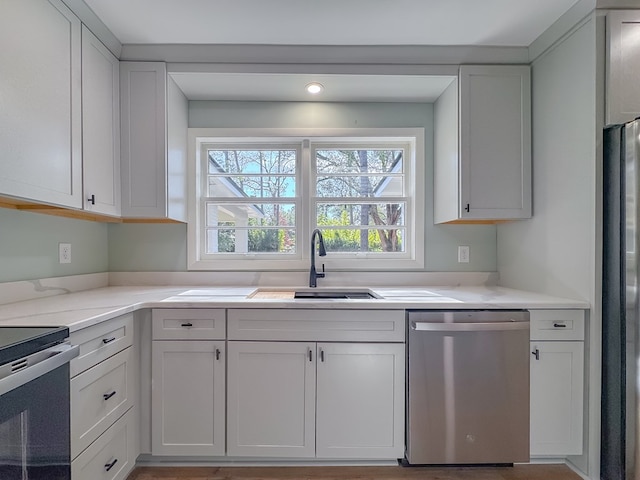 kitchen with sink, stainless steel appliances, white cabinetry, and light stone counters