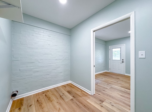 interior space featuring brick wall and light hardwood / wood-style floors