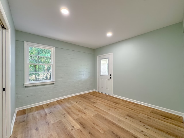 entrance foyer with brick wall and light hardwood / wood-style flooring