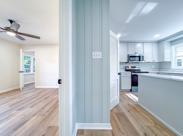 kitchen featuring appliances with stainless steel finishes, ceiling fan, light hardwood / wood-style flooring, and white cabinetry