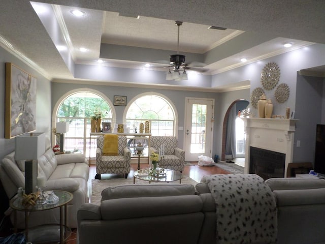 living room with ornamental molding, a ceiling fan, and a tray ceiling