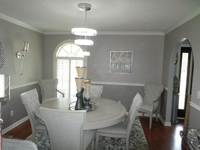 dining area featuring crown molding, arched walkways, and wood finished floors