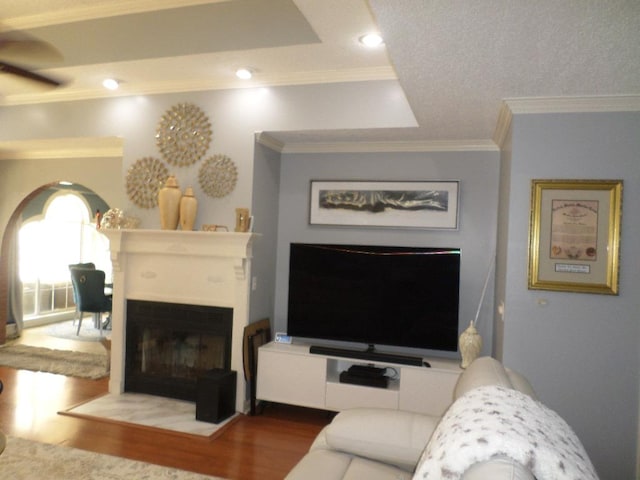 living room featuring ceiling fan, crown molding, a fireplace, wood finished floors, and recessed lighting