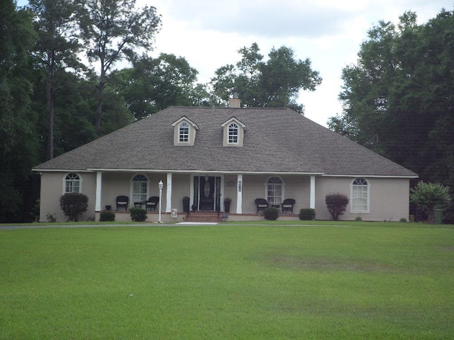 country-style home featuring covered porch, a shingled roof, and a front yard