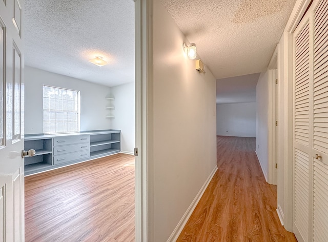 corridor featuring a textured ceiling and light hardwood / wood-style flooring