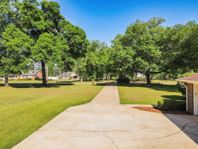 view of property's community featuring a yard and concrete driveway