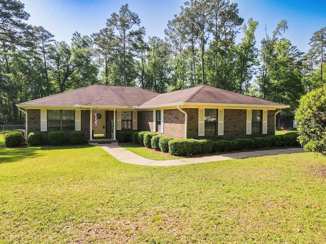 ranch-style home with a front lawn, brick siding, and fence
