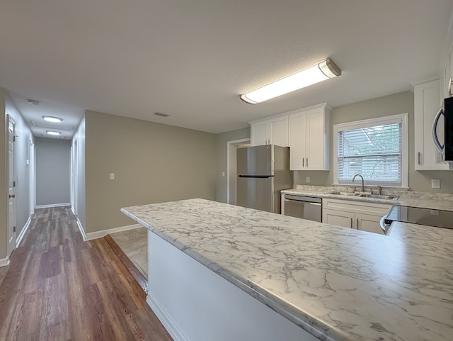 kitchen featuring white cabinetry, sink, stainless steel appliances, dark hardwood / wood-style flooring, and kitchen peninsula