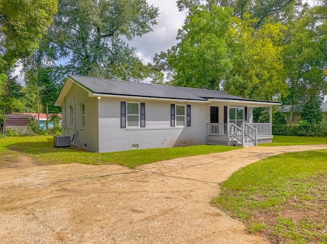 ranch-style home featuring cooling unit, covered porch, and a front yard