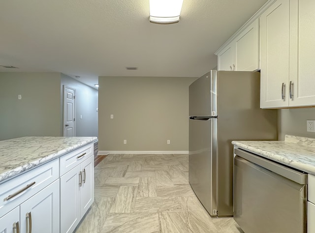 kitchen with light stone countertops, light parquet flooring, white cabinetry, and stainless steel dishwasher